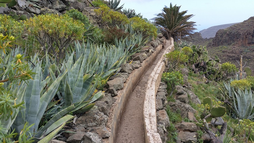 Levada, irrigatiekanaal tijdens wandeling van El Cercado naar La Calera, la Matanza, Wandelpad hoog boven Barranco de Erque tijdens wandeling op een wandelvakantie op La Gomera op de Canarische Eilanden